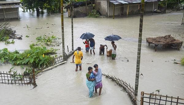 Villagers wade through a waterlogged street after their house submerged in floodwater during heavy rain, at Pathsala in Barpeta district, Sunday, July 12, 2020. Credit: PTI Photo
