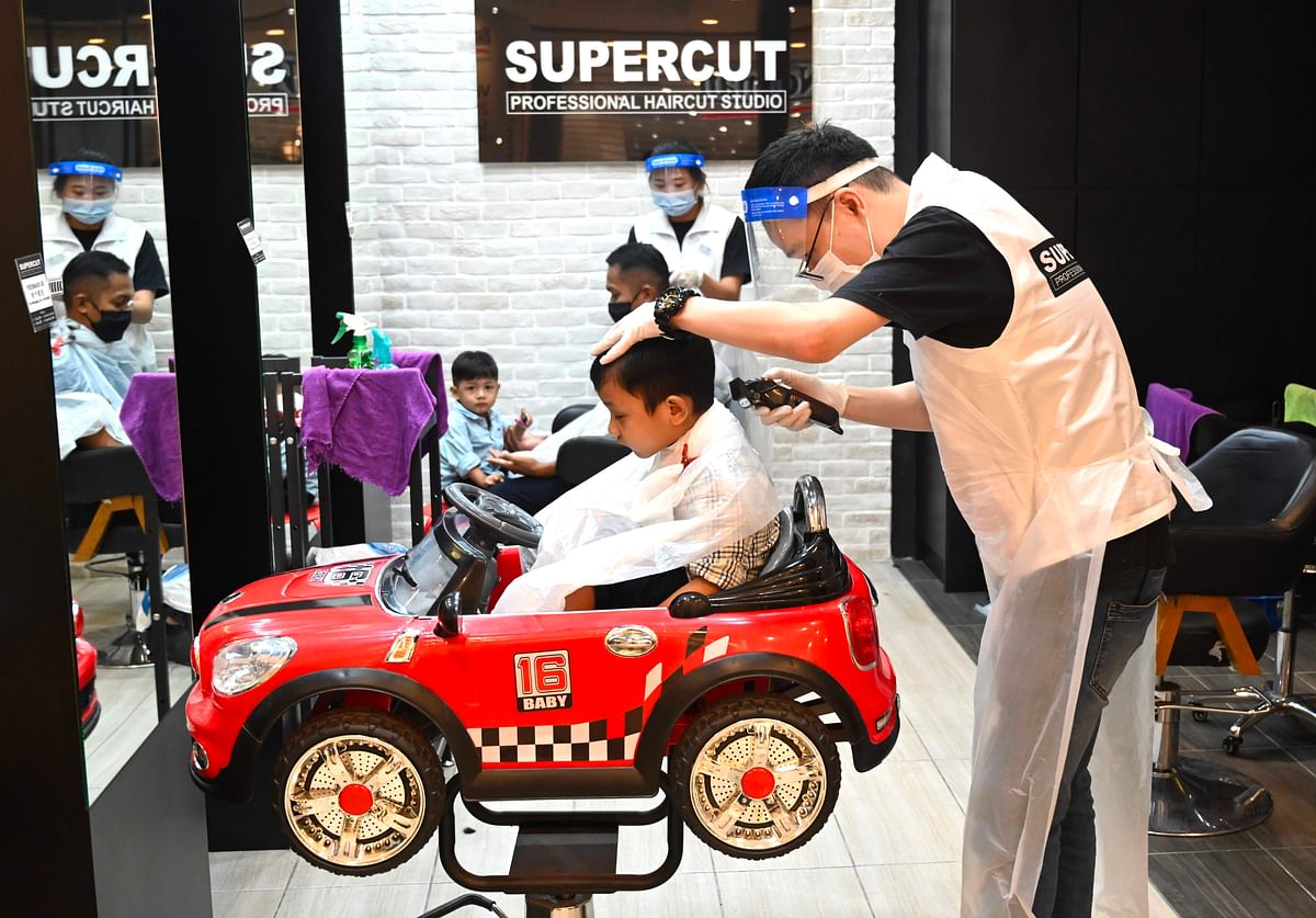 A boy gets his hair cut at a barber shop in Penang on July 16, 2020 after Malaysia's economy was reopened following restrictions to halt coronavirus. Credit: AFP