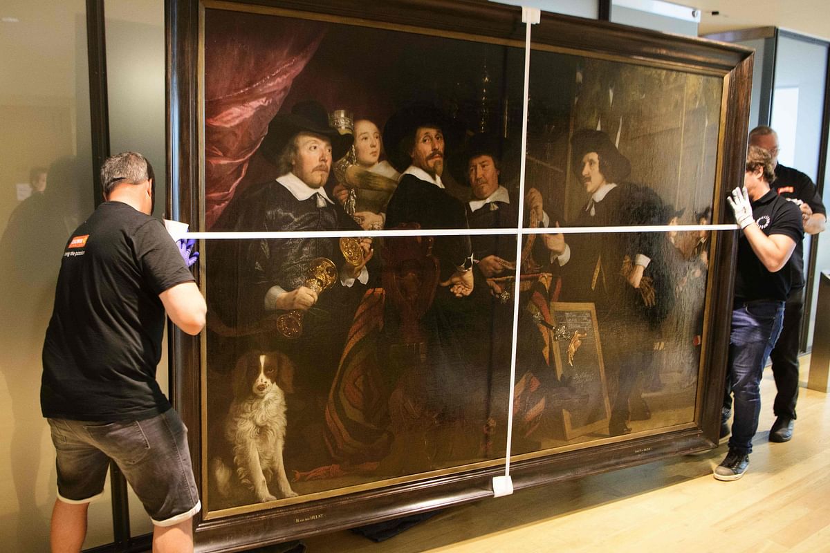 Workers hold the painting ‘Overlieden van de Handboogdoelen’ from 1653 by late Dutch artist Bartholomeus van der Helst at The Hermitage Museum in Amsterdam, The Netherlands, on July 15, 2020. Credit: AFP Photo