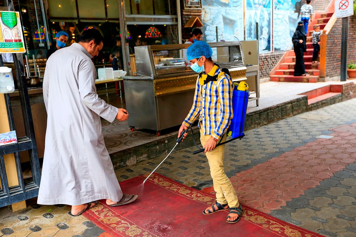 A Yemeni man disinfect the feet of a man at the entrance of a park in the Yemeni capital Sanaa on July 16, 2020, following the easing of measures against the COVID-19 novel coronavirus pandemic. Credit: AFP