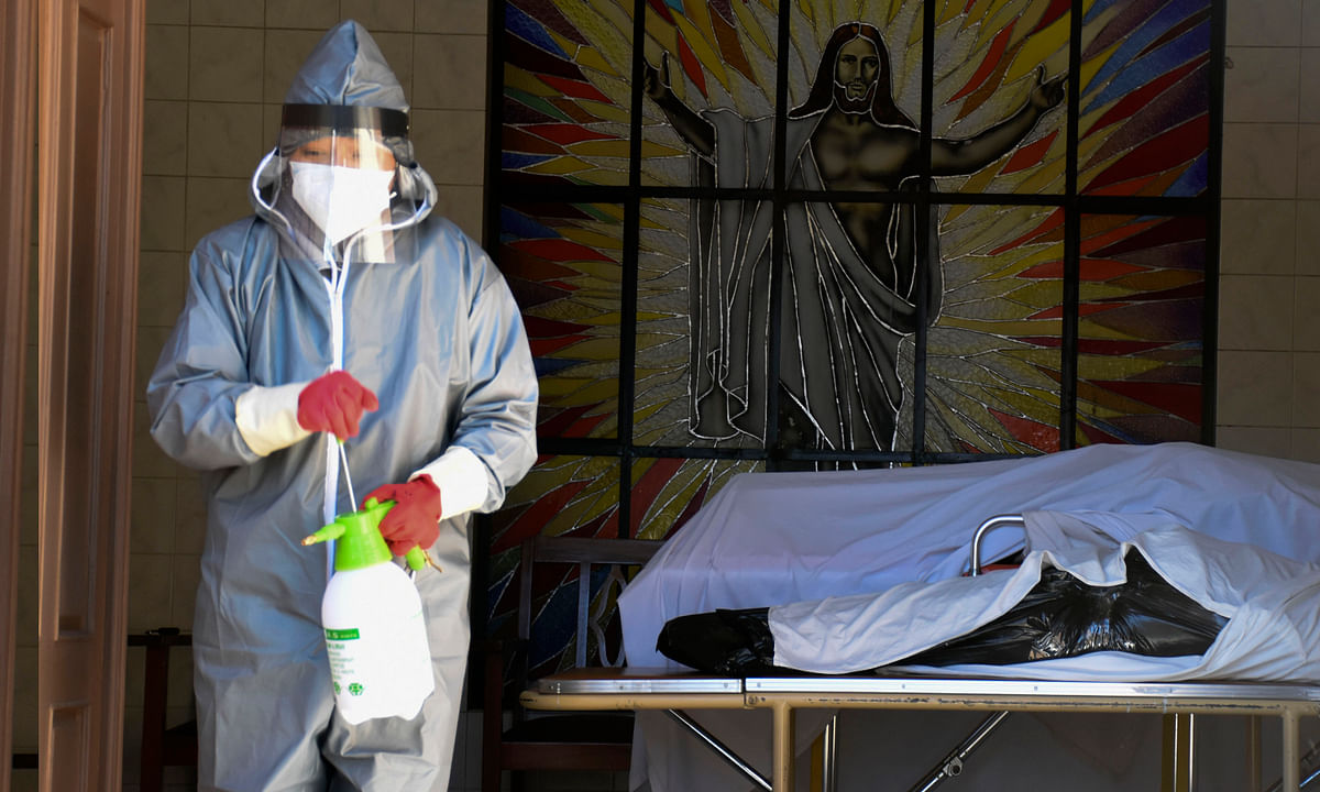 A health worker dressed in full protective gear to protect himself from the spread of the new coronavirus disinfects the area near the coffin with remains of an elderly man stands, at the San Jose nursing home in Cochabamba, Bolivia, Thursday, July 16, 2020. According to city authorities, 10 elderly people with suspected COVID-19 symptoms have died in the last two weeks at the nursing home. Credit: AP/PTI Photo