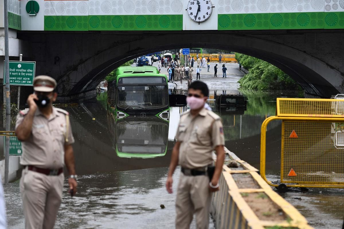 Policemen stand along Minto road where vehicles got stuck under the water-logged Minto Bridge following heavy early morning rains in New Delhi. Credit: AFP