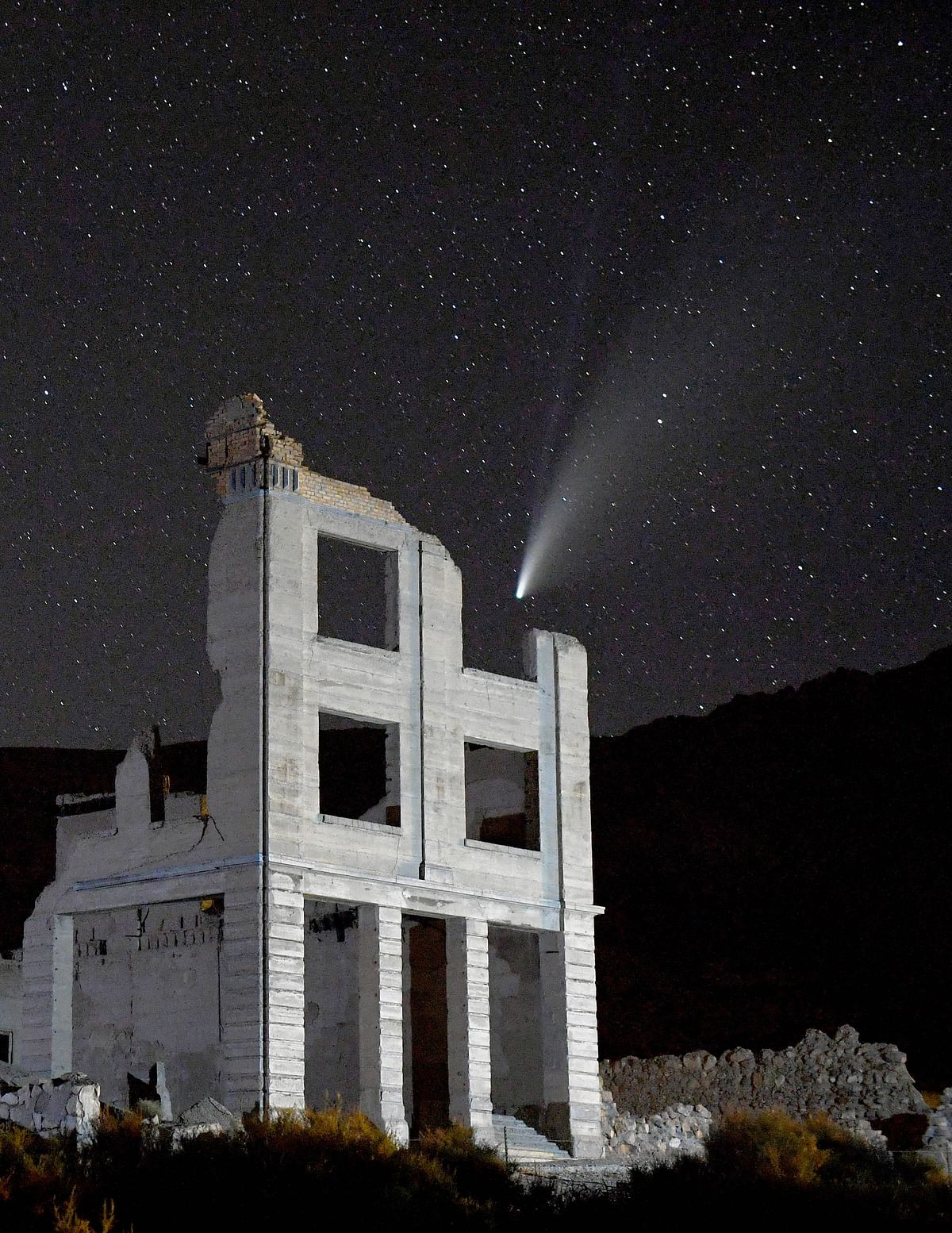 The Comet NEOWISE (C/2020 F3) is seen above the ruins of the Cook Bank building on July 20, 2020 in the ghost town of Rhyolite, Nevada. The comet is named after NASA's Near-Earth Object Wide-field Infrared Survey Explorer, which discovered it in March. It is about 3 miles wide and 70 million miles from Earth while traveling at 144,000 mph as it moves away from the sun. Credit: Getty Images/AFP