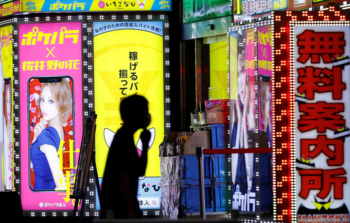 A man wearing a face mask walks past a signboard of a bar in the Kabukicho district, amid the coronavirus disease (Covid-19) outbreak in Tokyo, Japan, July 14, 2020. Credit: REUTERS