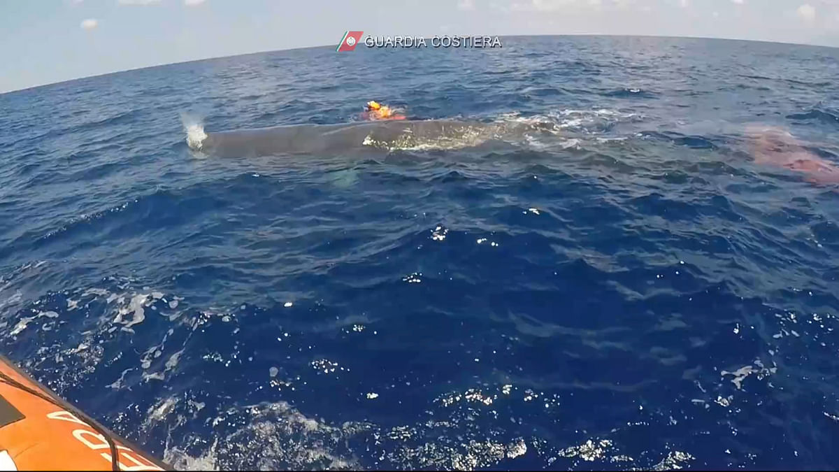 Italian coastguard divers work to free a sperm whale caught in a fishing net at sea north of the Sicilian Aeolian Islands in this still image taken from a video, July 19, 2020. Picture taken July 19, 2020. Credit: Italian coastguard/REUTERS