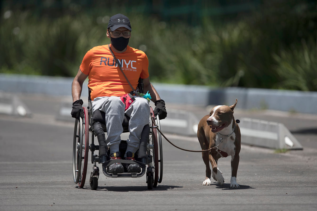 A man wearing a mask to curb the spread of the new coronavirus and riding a wheelchair exercises with his dog in Chapultepec Park, Mexico City, Sunday, July 19, 2020. Credit: AP/PTI Photo