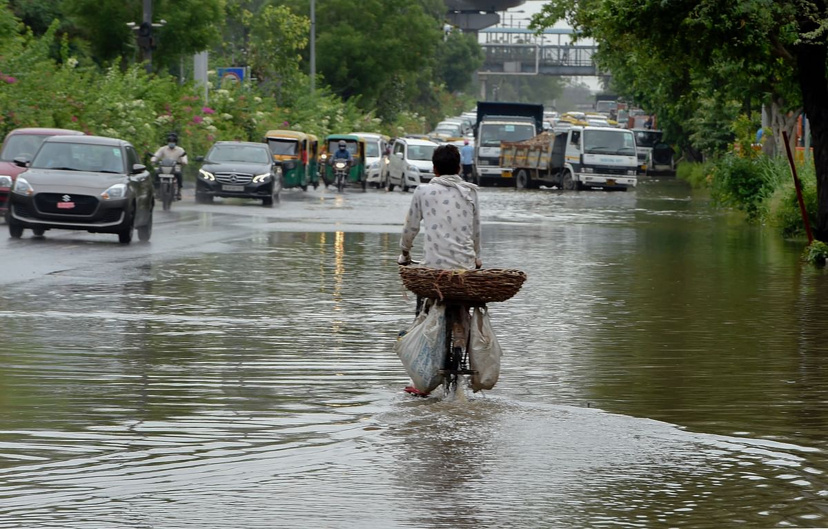 Commuters pass through a waterlogged street, following monsoon rain, in New Delhi, Monday, July 20, 2020. Credit: PTI Photo