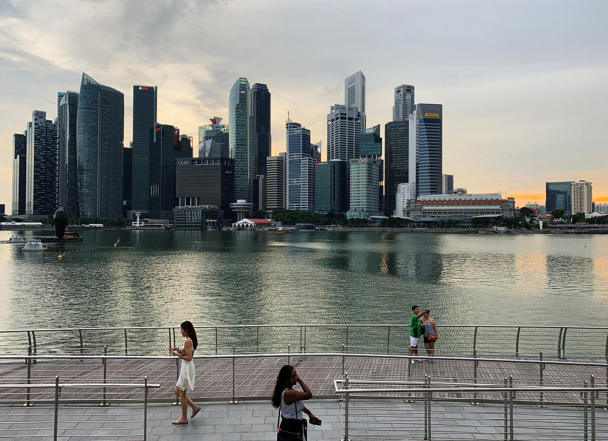 Passers-by walking in front of Singapore's central business district skyline. Credit: Reuters