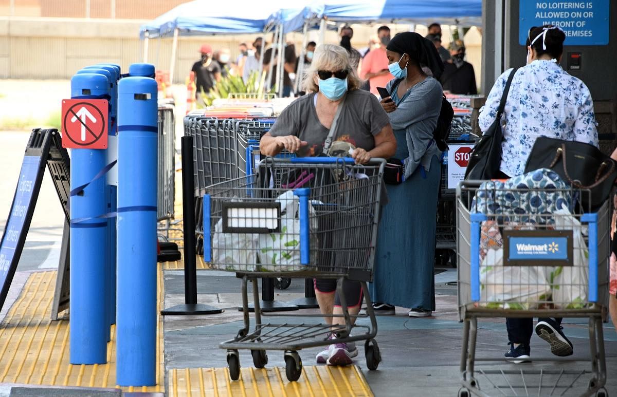A woman wearing a facemask pushes a cart outside Walmart. Credit: AFP