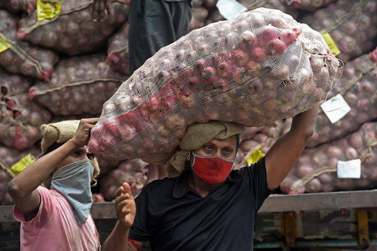 Workers unload a sack of onions from a truck at a wholesale vegetable market in Mumbai. Credit: AFP