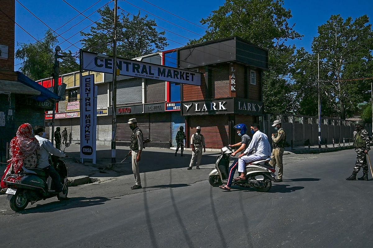 Security personnel stop motorists on a street of a closed market during a lockdown in Srinagar. Credit AFP