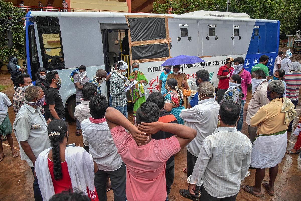 People flout social distancing norms while waiting near a mobile swab collection vehicle for Covid-19 test. Credit: PTI