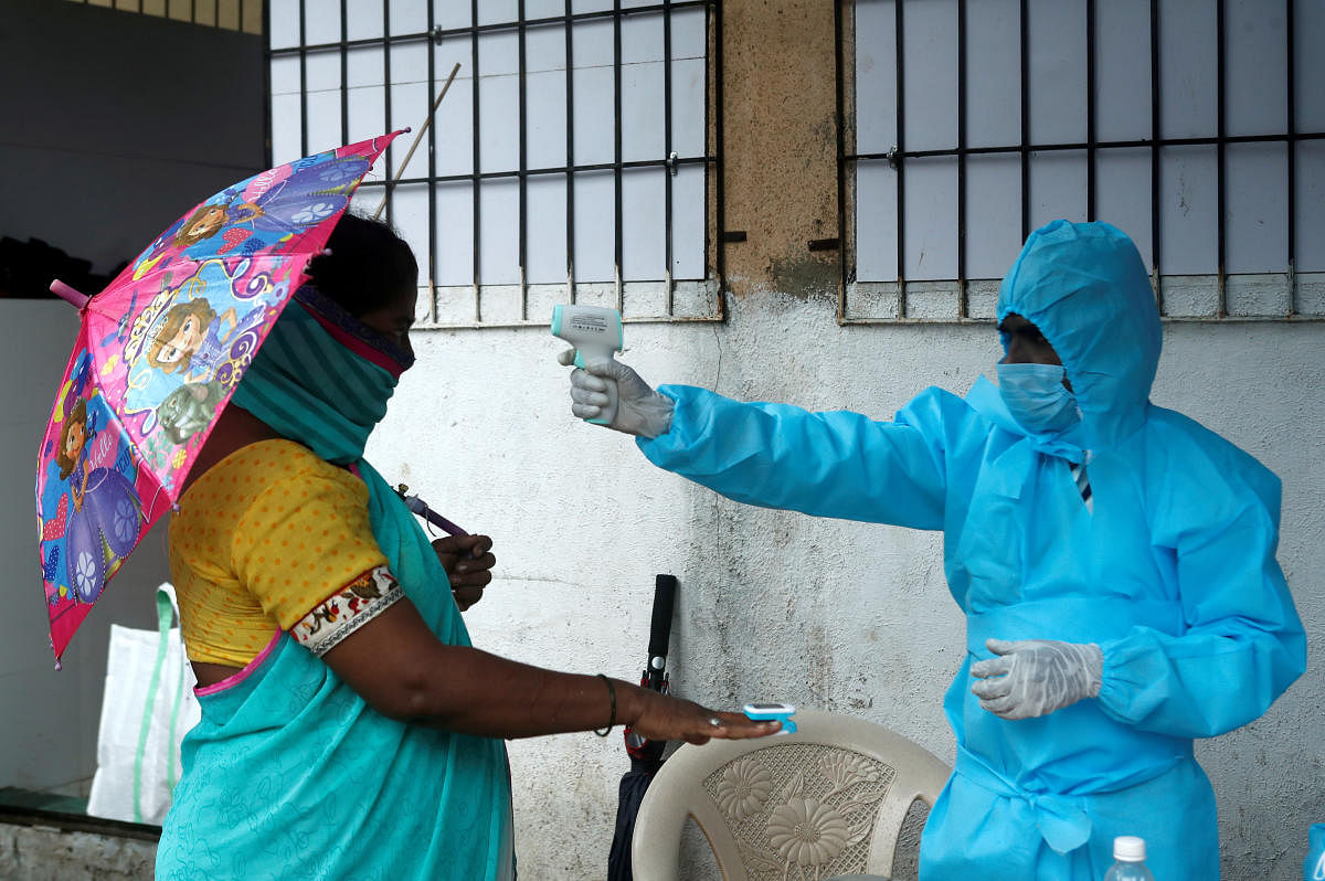 A healthcare worker checks the temperature and pulse of a resident during a check-up camp for the coronavirus disease (COVID-19), in Mumbai. Credit: Reuters