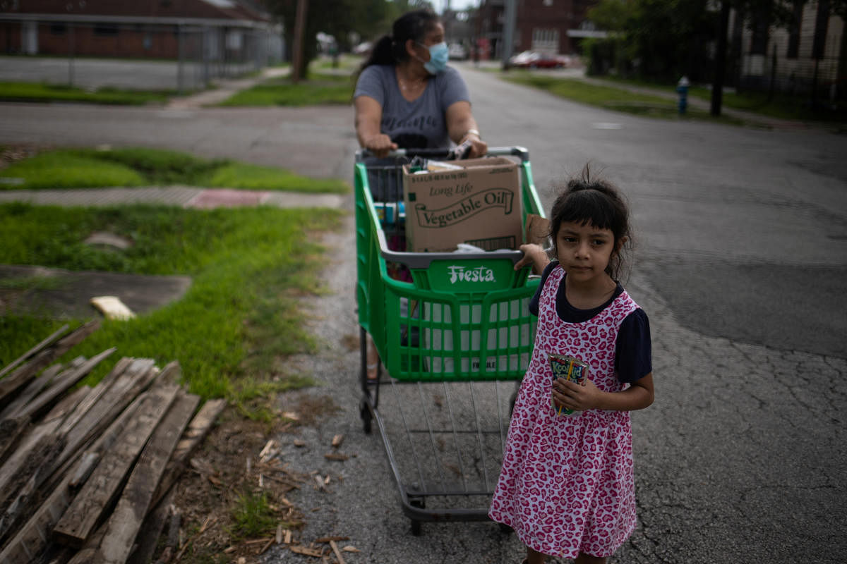 Amber, 5, helps her grandmother Minerva Delgado pull a cart with groceries distributed by the Wesley Community Center to residents affected by the economic fallout caused by the coronavirus disease outbreak in Houston. Credit: Reuters