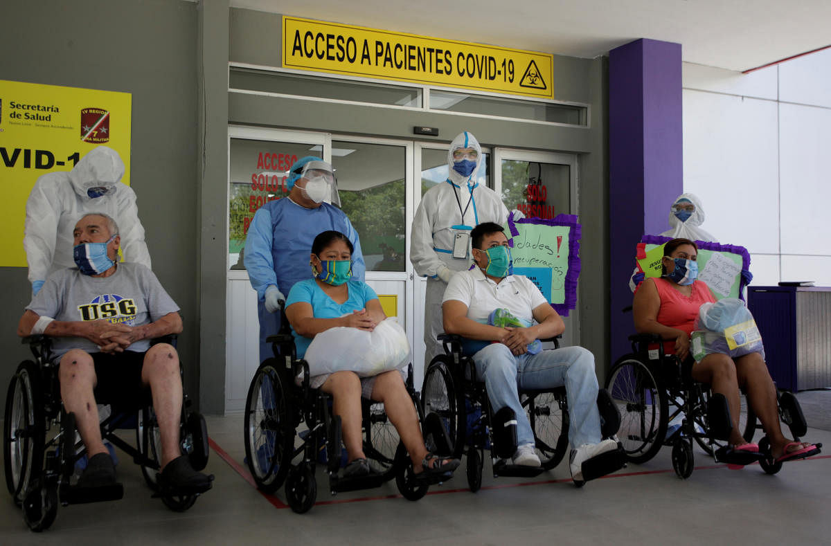 Patients who recovered from the coronavirus disease sit in wheelchairs after being released from the