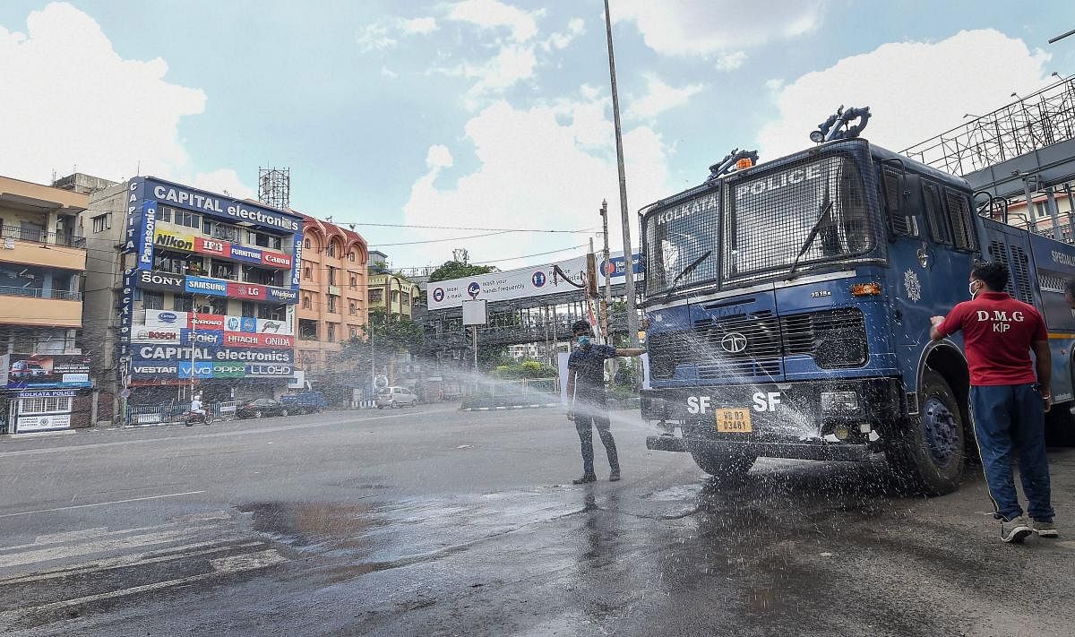 Police personnel sanitize a street during the complete lockdown on weekends to curb the spread of coronavirus disease, in Kolkata. Credit: PTI