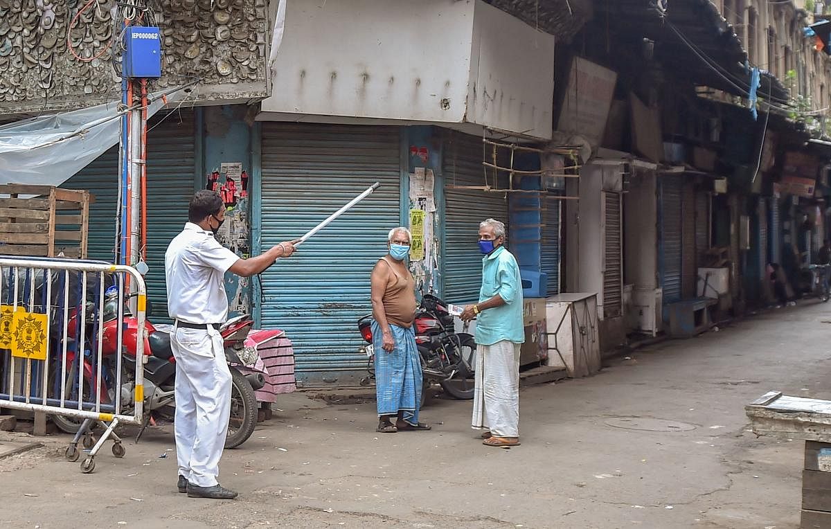 A policeman instructs local residents to go back their houses during a complete lockdown to curb the spread of coronavirus, in Kolkata. Credit: PTI