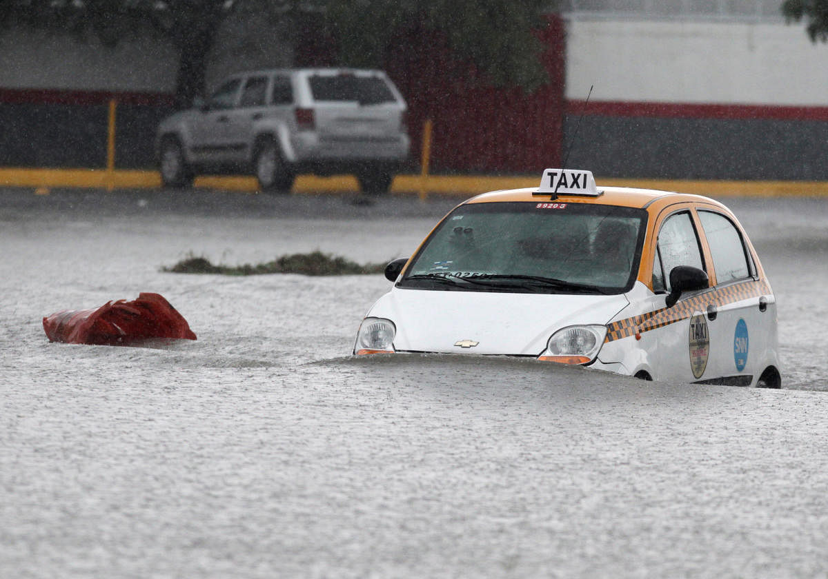 A taxi driver is seen crossing a flooded street during the Storm Hanna in Apodaca on the outskirts of Monterrey, Mexico. Credit: Reuters Photo