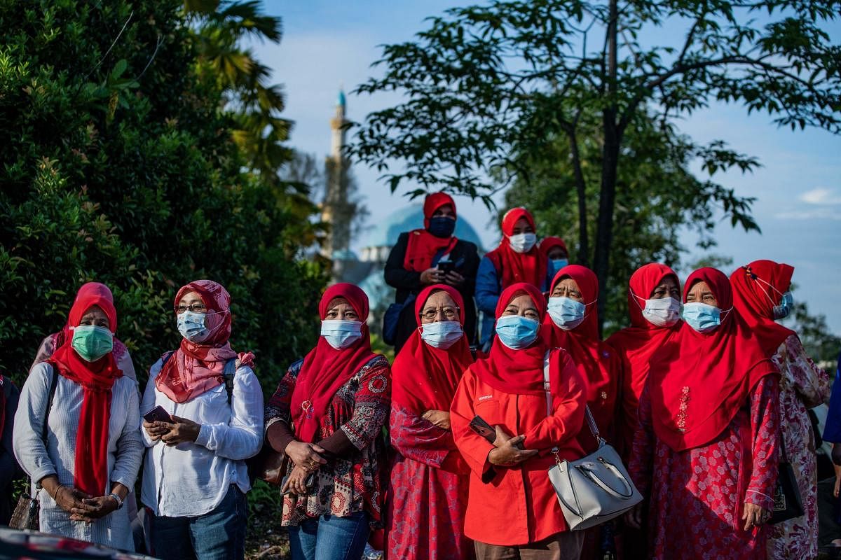 Supporters of Malaysia's former prime minister Najib Razak wear face masks while standing outside the gate of the Duta Court complex awaiting a verdict in his corruption trial in Kuala Lumpur on July 28, 2020. Credit: AFP Photo