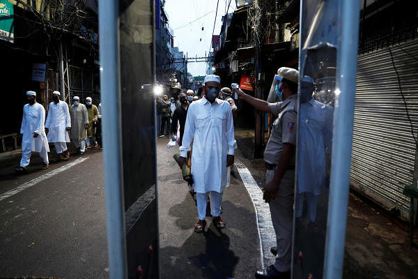 A policeman checks the temperature of Muslims arriving to offer Eid al-Adha prayers at the Jama Masjid. Credit: Reuters