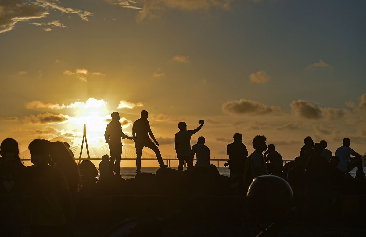 People click pictures at Dadar Chowpatty promenade during the sunset, in Mumbai, Sunday, Aug 2, 2020. Credit: PTI Photo