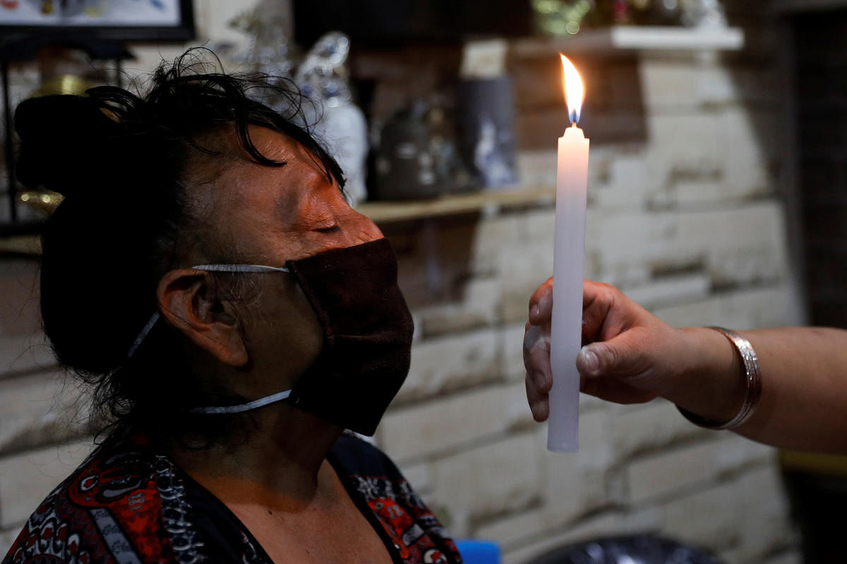 Rosa Dominguez, who is looking to improve her health and her economic situation due to the present coronavirus disease (COVID-19) outbreak, chants as esoteric witch Karina, conducts a spiritual cleansing to her, at the Sonora market, in Mexico City. Credit: Reuters