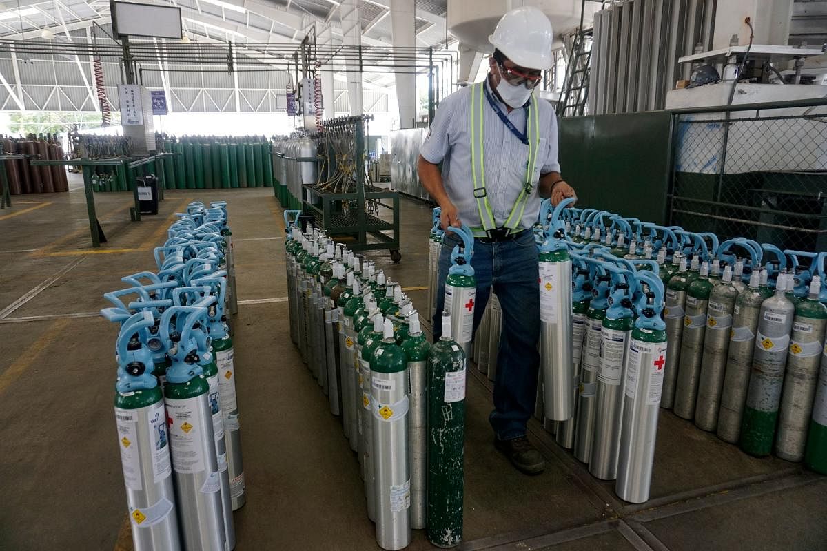 An employee at Productos del Aire, the largest oxygen distribution company in Central America, arranges oxygen bottles, refilled to be distributed to hospitals and people infected with the novel coronavirus, in Guatemala City. Credit: AFP