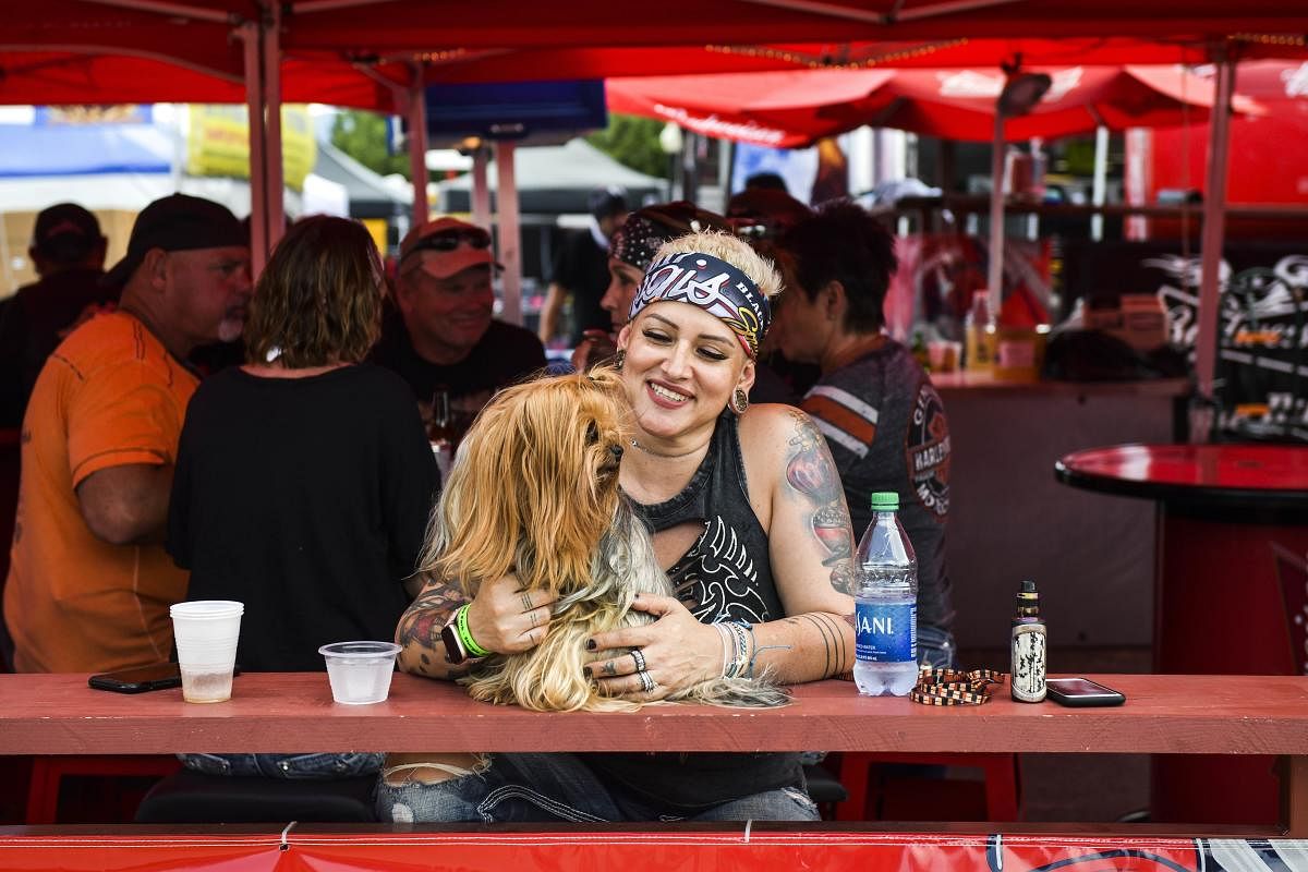 Barbie Richardson sits at an outdoor bar with her dog, Boss, a day before the start of the Sturgis Motorcycle Rally. Credit: AFP