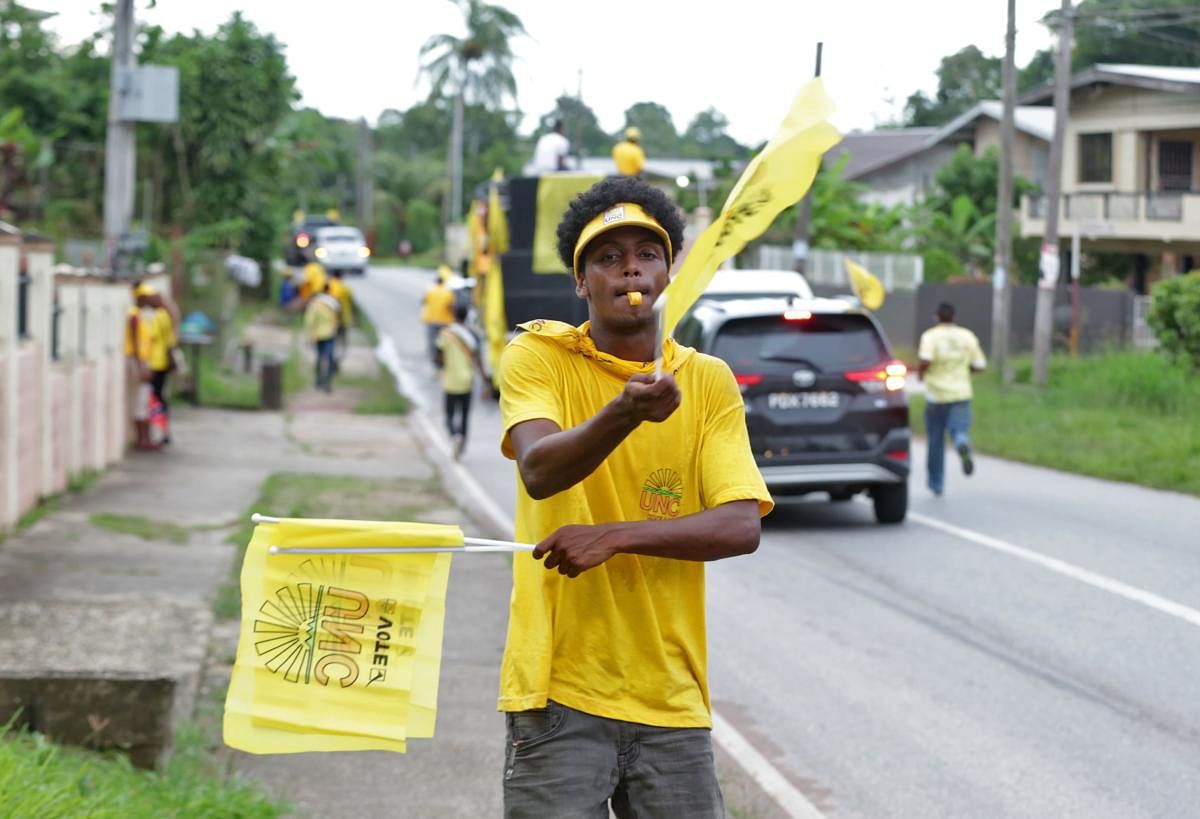 A supporter of Trinidad and Tobago's former prime minister Kamla Persad-Bissessar, leader of the opposition United National Congress (UNC), waves flags as he stands along the way during a motorcade as part of the closing rally of Persad-Bissessar's campaign ahead of the election, in Siparia south of Trinidad and Tobago, a twin-island nation off Venezuela, on August 9, 2020 amid the Covid-19 novel coronavirus pandemic. AFP