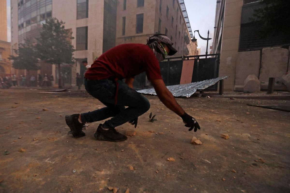 A Lebanese protester picks stones amid clashes with security forces near an access street to the parliament in central Beirut on August 9, 2020, following a deadly explosion that turned the city into a disaster zone. AFP