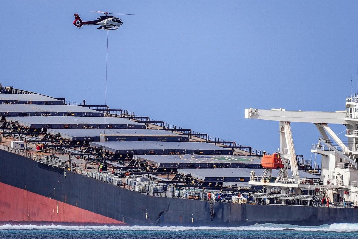 A helicopter hovers over the vessel MV Wakashio, belonging to a Japanese company but Panamanian-flagged, that ran aground and caused oil leakage near Blue bay Marine Park in southeast Mauritius on August 8, 2020. - France on August 8, 2020 dispatched aircraft and technical advisers from Reunion to Mauritius after the prime minister appealed for urgent assistance to contain a worsening oil spill polluting the island nation's famed reefs, lagoons and oceans. AFP