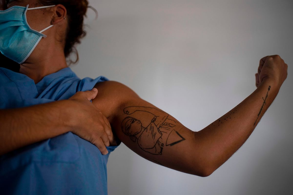 A Spanish health worker and volunteer of the SAMU Foundation shows a symbolic tattoo while putting on the level III biosafety suit to enter the intensive care unit of El Salvador Hospital. Credit: AFP