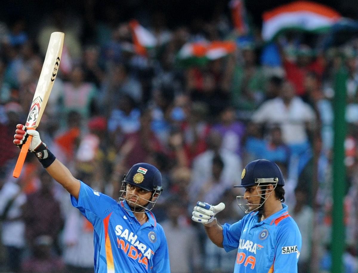 Indian batsman Suresh Raina is watched by teammate and former captain Mahendra Singh Dhoni as he raises his bat to the crowd after scoring a half-century during the first ODI cricket match between India and England. Credit: AFP Photo
