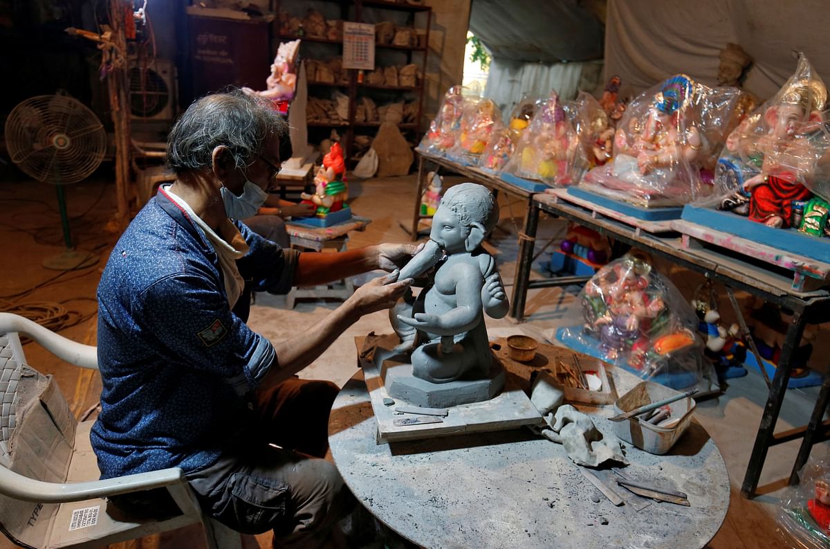 An artisan wearing a face mask works on an idol of Hindu god Ganesh, the deity of prosperity, at his workshop ahead of the Ganesh Chaturthi festival, amidst the coronavirus disease (COVID-19) outbreak, in Ahmedabad. Credit: Reuters