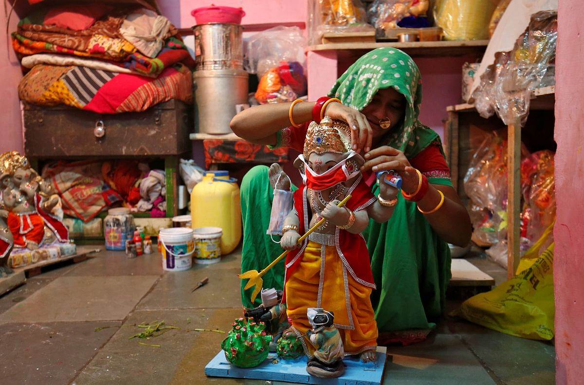 A woman puts a face mask on an idol of Hindu god Ganesh, the deity of prosperity, at her workshop ahead of the Ganesh Chaturthi festival, amidst the coronavirus disease (COVID-19) outbreak, in Ahmedabad. Credit: Reuters
