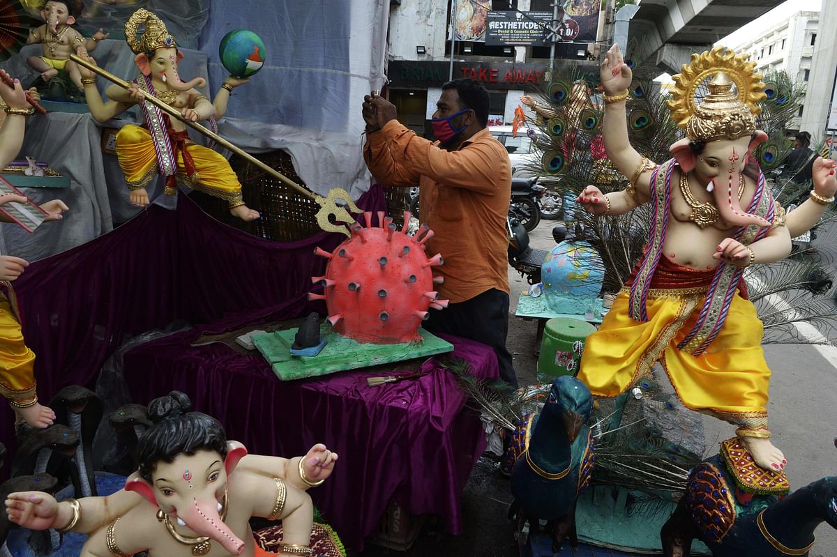 A devotee takes picture of a COVID-19 coronavirus themed elephant headed Hindu god Ganesha idol at a workshop ahead of the Ganesh Chaturthi festival in Hyderabad. Credit: AFP