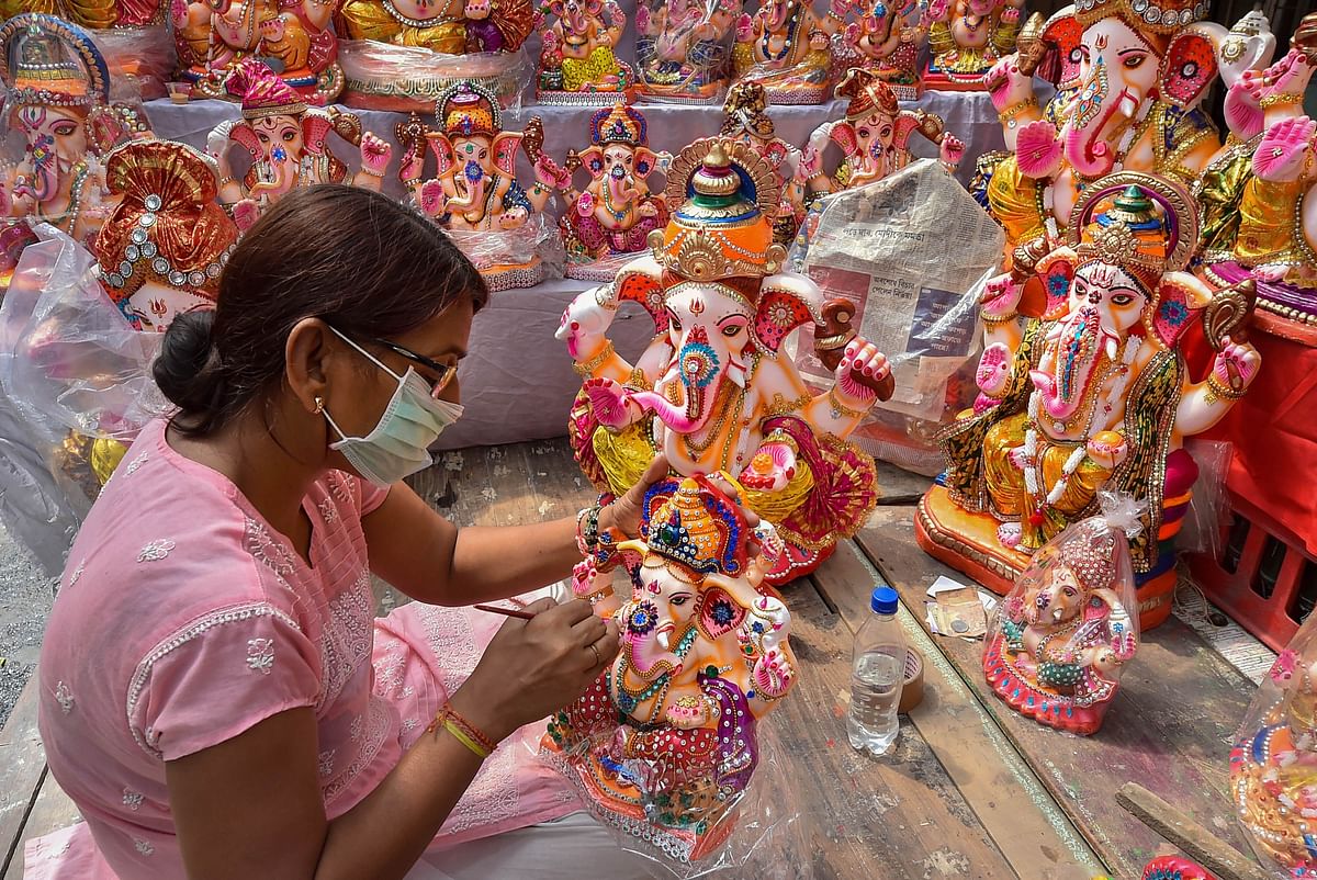 An artisan gives a finishing touch to an idol of Lord Ganesh ahead of the Ganesh Chaturthi festival, at her workshop in Kumartuli, Kolkata. Credit: PTI