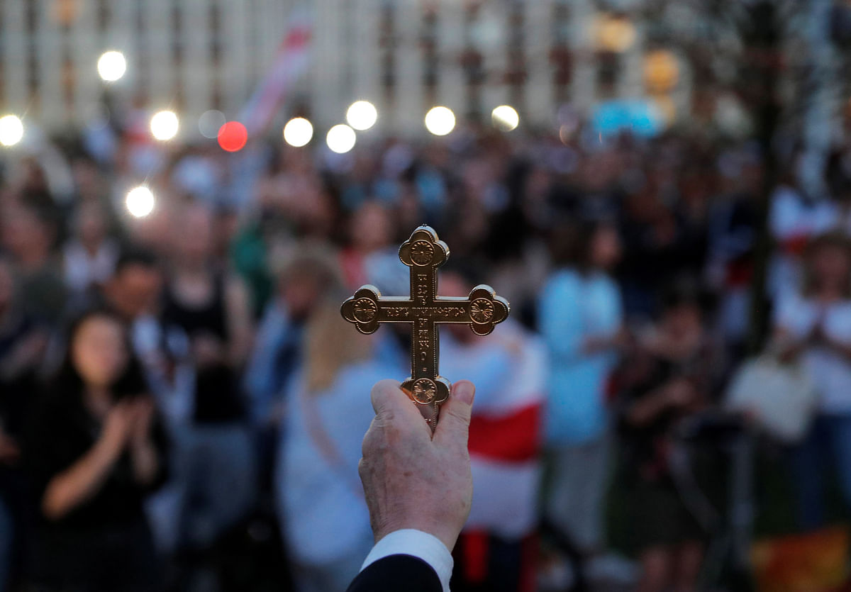 A priest holds a cross as he stands in front of participants during an opposition demonstration to protest against presidential election results at the Independence Square in Minsk, Belarus. Credit: Reuters Photo