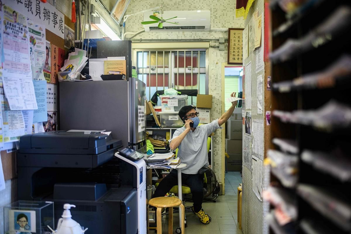 In this picture taken on August 19, 2020, district councillor Chow Wai-hung, who was arrested under the National Security Law while holding placards during a protest at a Yuen Long shopping mall, takes a phone call during an interview with AFP at his office in Hong Kong. AFP