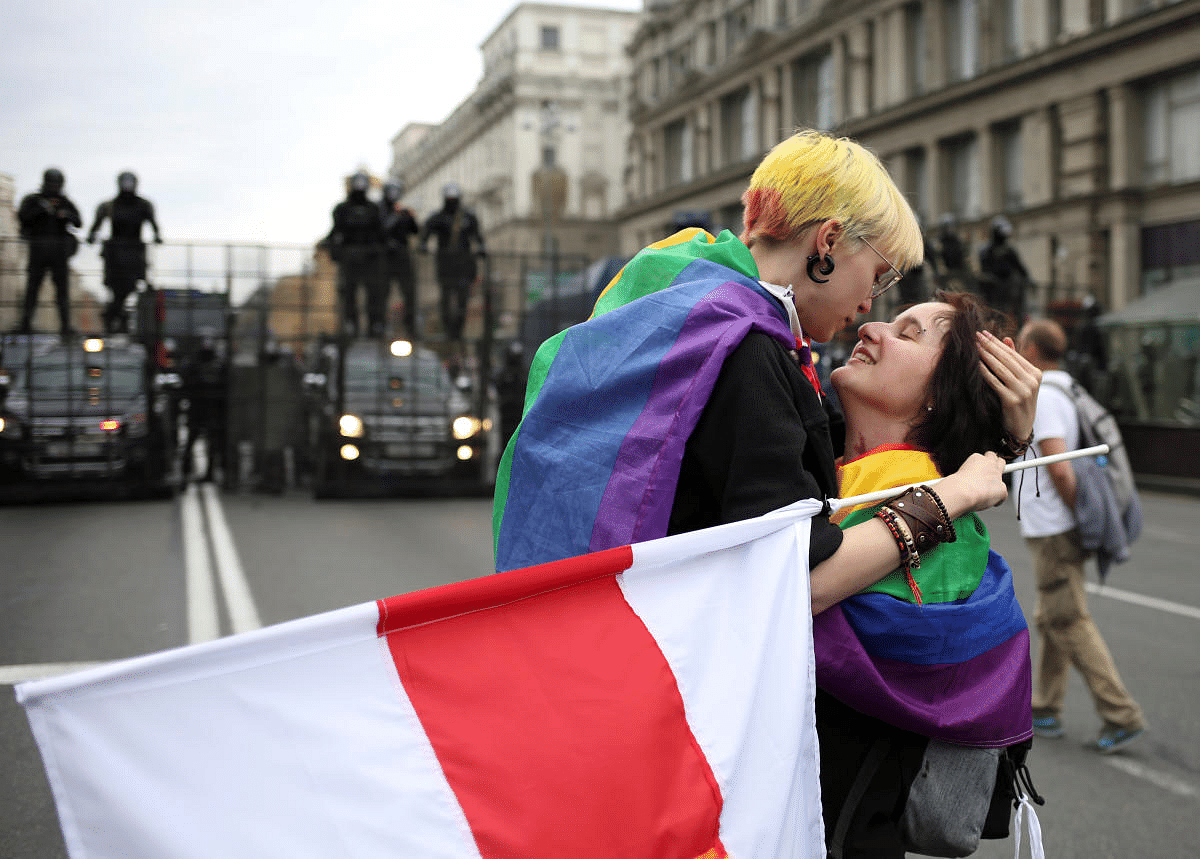Participants with rainbow-themed flags, representing the LGBT symbol, embrace near barriers erected by Belarusian law enforcement officers during an opposition rally to protest against police brutality and to reject the presidential election results in Minsk, Belarus. Credit: Reuters Photo
