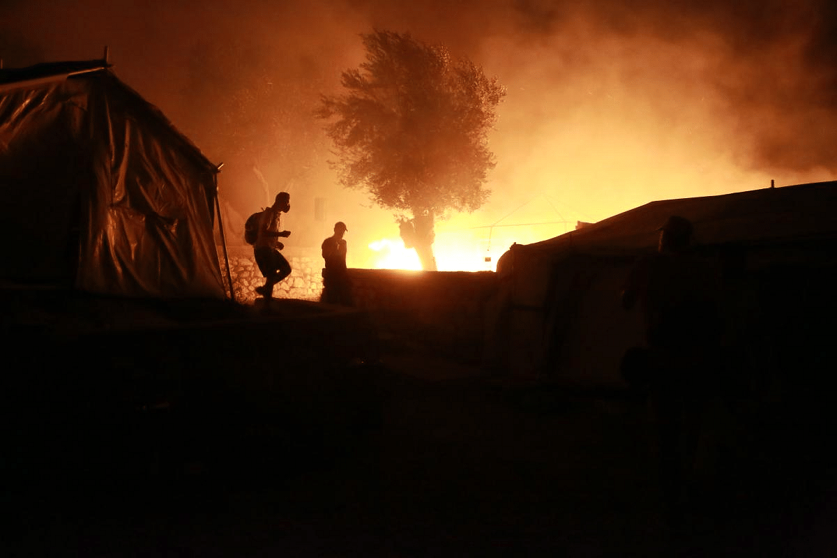 Migrants walk inside the Moria camp on the island of Lesbos during a major fire there on September 9, 2020. Credit: AFP Photo
