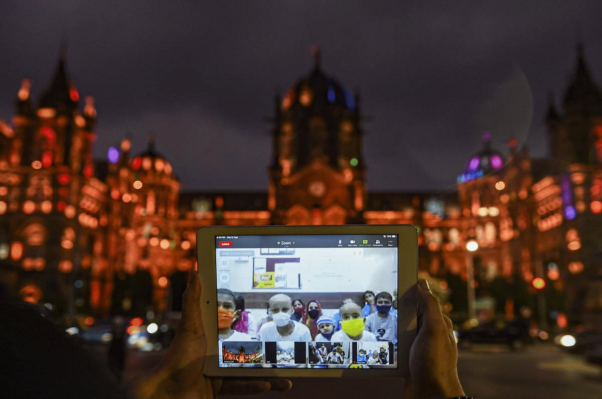 A volunteer interacts with cancer patients as he shows them the Chhatrapati Shivaji Maharaj Terminus, illuminated to raise awareness on childhood cancer patients, in Mumbai. Credit: PTI Photo