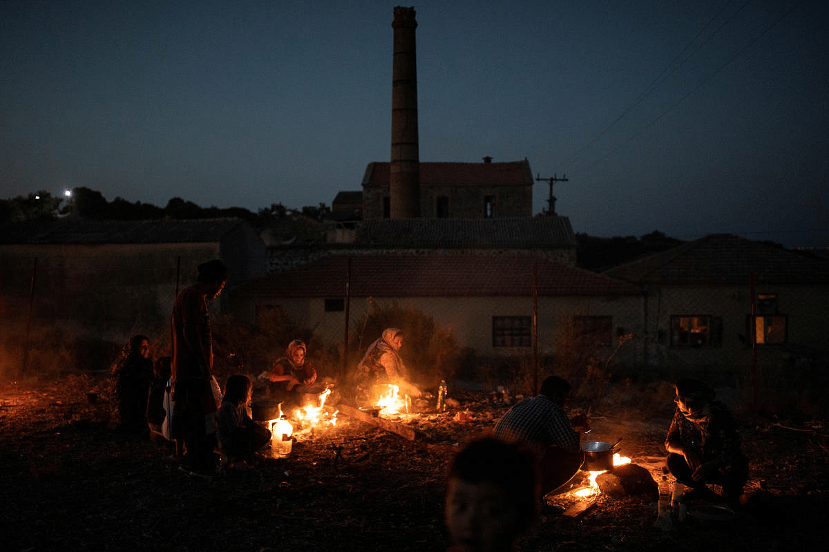Refugees and migrants from the destroyed Moria camp cook over a fire, on the island of Lesbos, Greece. Credit: Reuters Photo