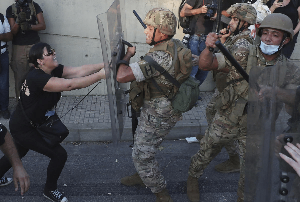 An anti-government protester clashes with Lebanese soldiers, during a protest against the Lebanese President Michel Aoun near the presidential palace, in Baabda east of Beirut, Lebanon. Credit: AP Photo