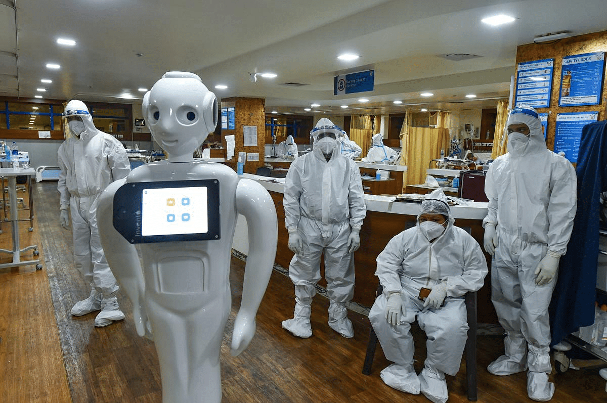 A robot operates inside a Covid-19 dedicated ward as health workers look on, at Yatharta Hospital in Greater Noida.The robot is capable of facilating communication between COVID-19 patients and their family member besides symptom and thermal checking.  Credit: PTI Photo