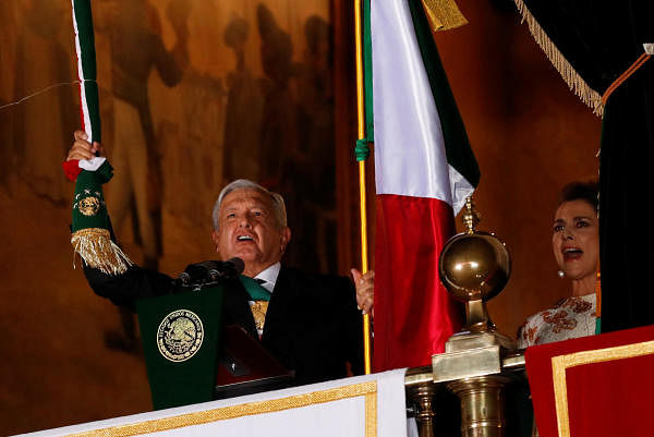 Mexico's President Andres Manuel Lopez Obrador holds the national flag as he shouts the