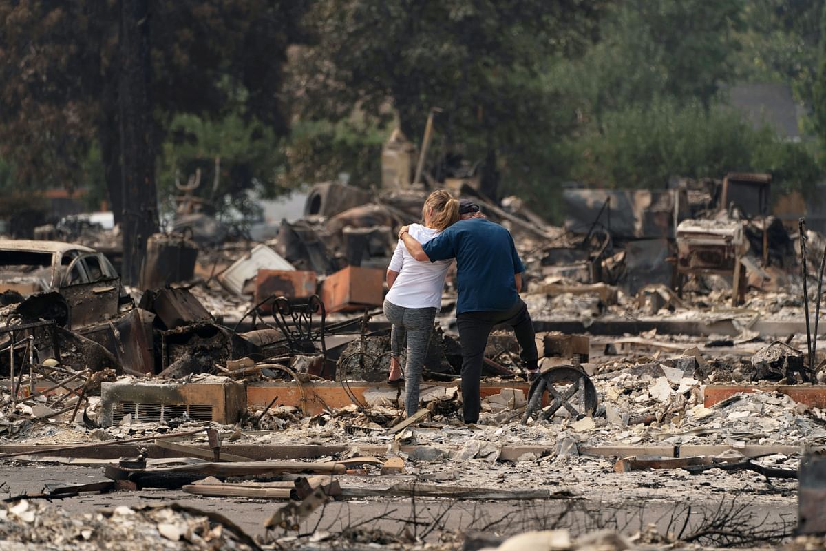 Christina Mitchell embraces her fiance, George Schmoll, amidst the remnants of their apartment after losing items such as her wedding dress and his wedding ring for their December wedding, now postponed, after a wildfire came through the area in Phoenix, Oregon, US. Credit: Reuters