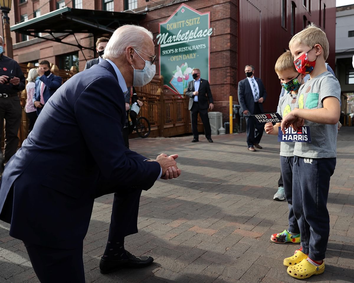 Democratic US presidential nominee and former Vice President Joe Biden talks with two young boys holding Biden Harris campaign stickers during an unscheduled walk on the street while campaigning in Duluth, Minnesota. Credit: Reuters