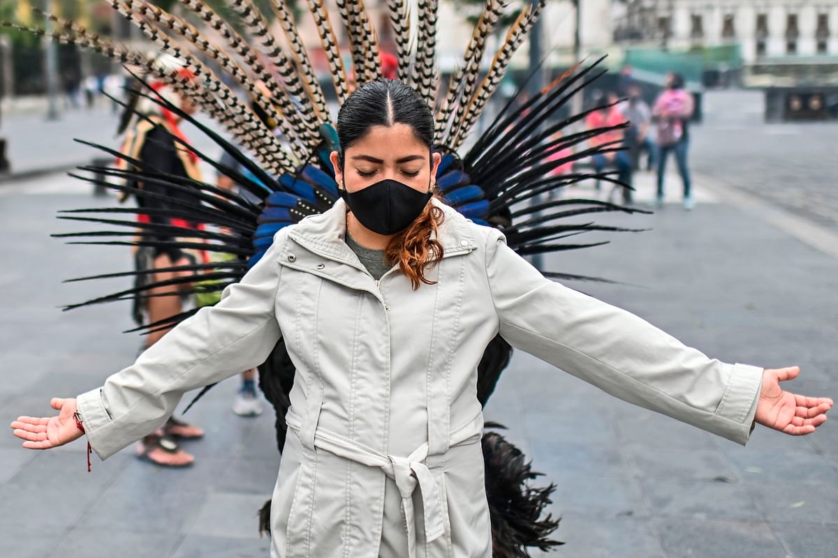 A Pre-Hispanic dancer performs an energetic cleansing ritual on a woman at downtwon in Mexico City, on September 18, 2020, amid the Covid-19 coronavirus pandemic. Credit: AFP