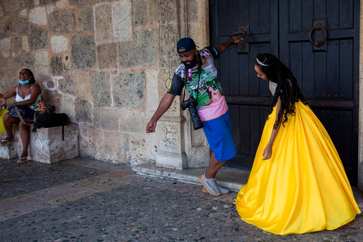 A photographer directs a young woman during a photography session in the Colonial Zone of Santo Domingo on September 12, 2020. - The Dominican Republic is used to doing photo sessions at parties, but in the times of the Covid-19 pandemic many people have chosen to do only the photo sessions instead of the celebration. Credit: AFP